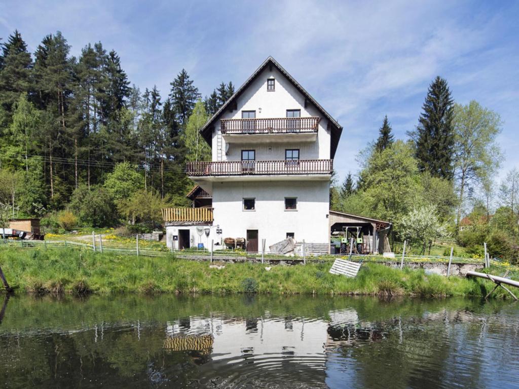a house on the side of a body of water at Alluring Apartment in Sch nsee in the forest in Schönsee