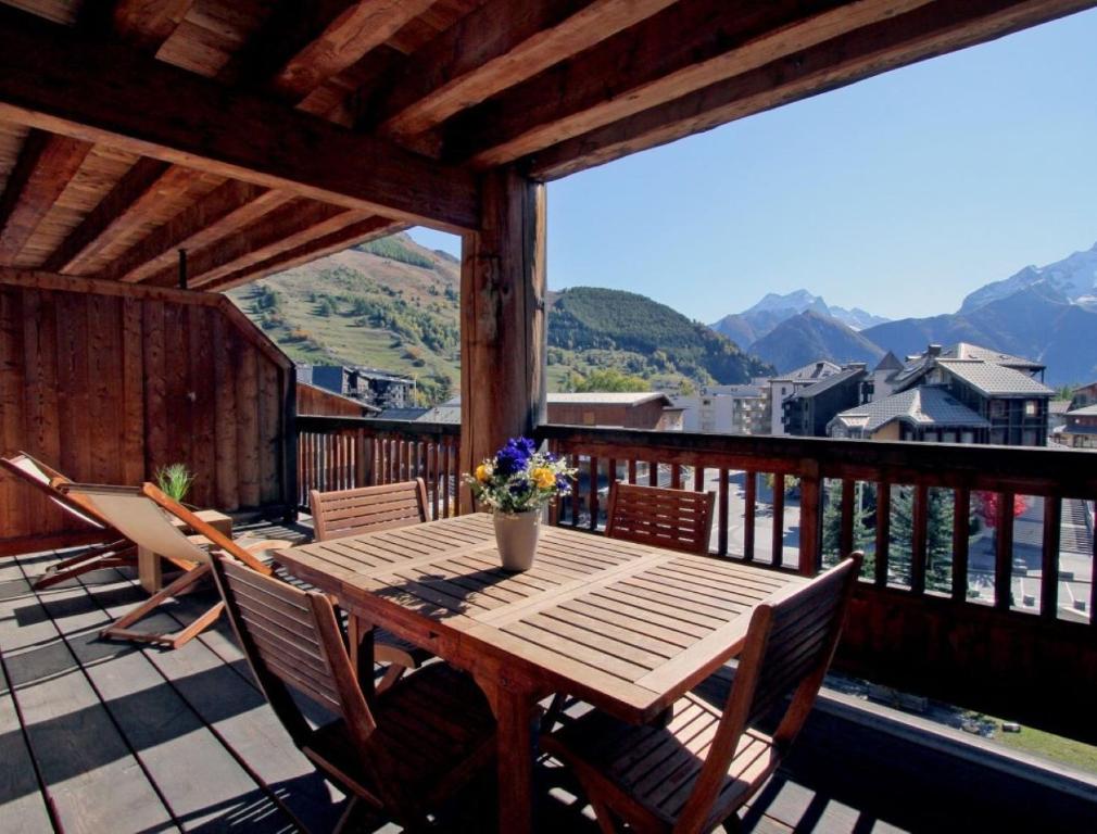 una mesa de madera y sillas en un balcón con vistas en Cortina 32 Appt terrasse somptueuse 4-6 pers, en Les Deux Alpes