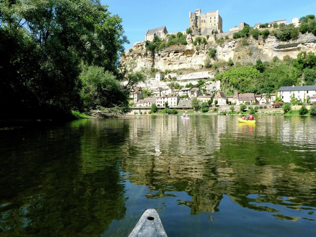 a boat on a river with a castle in the background at Snug cottage in Saint Eutrope De Born with pool in Saint-Eutrope-de-Born