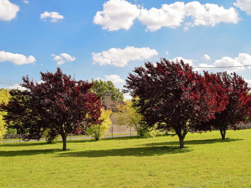 three trees with red leaves in a field at Snug cottage in Saint Eutrope De Born with pool in Saint-Eutrope-de-Born