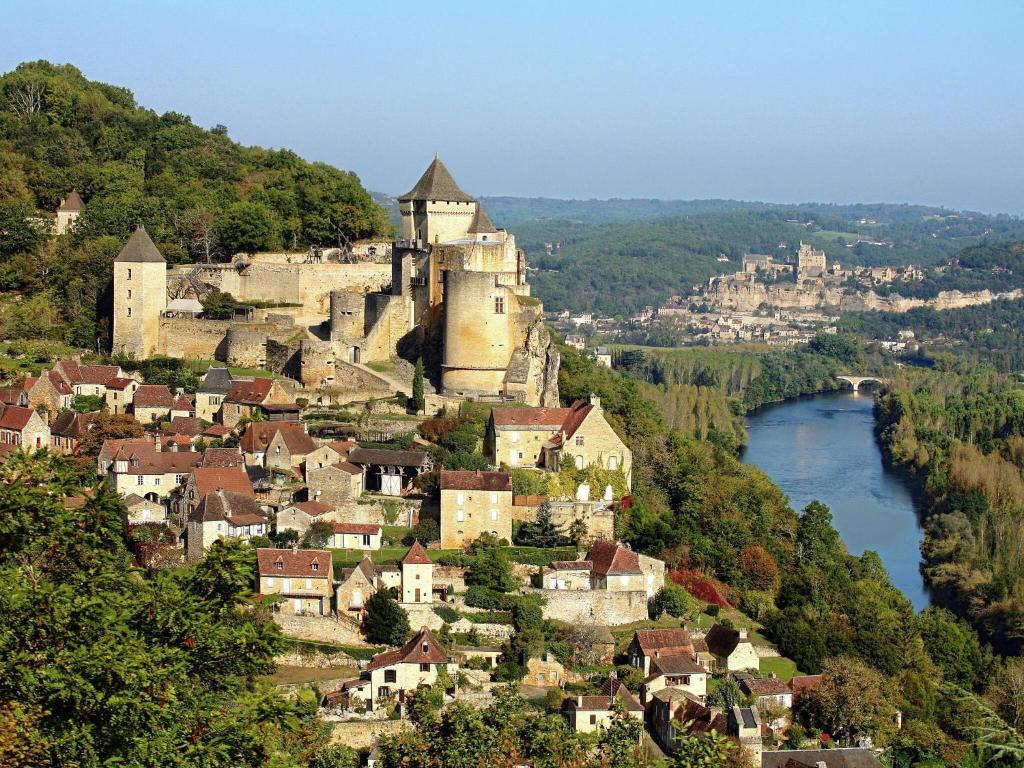 a town on a hill with a castle and a river at Snug cottage in Saint Eutrope De Born with pool in Saint-Eutrope-de-Born