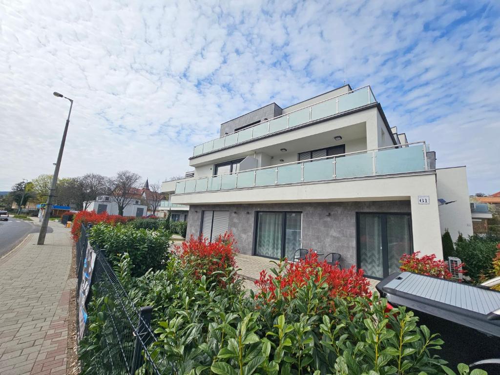 a white building with red flowers in front of it at ILK Residence in Balatonalmádi