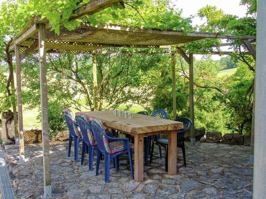 a wooden table and chairs under a pergola at Snug cottage in Saint Eutrope De Born with pool in Saint-Eutrope-de-Born