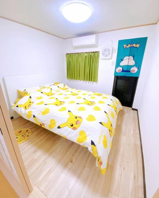 a bedroom with a bed with a yellow and white comforter at Pokémon Sleep 宝可梦的家 in Osaka