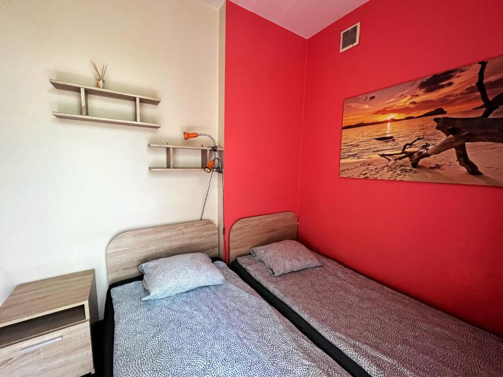 a room with two beds and a red wall at Cosy room Aleja Kijowska in Krakow