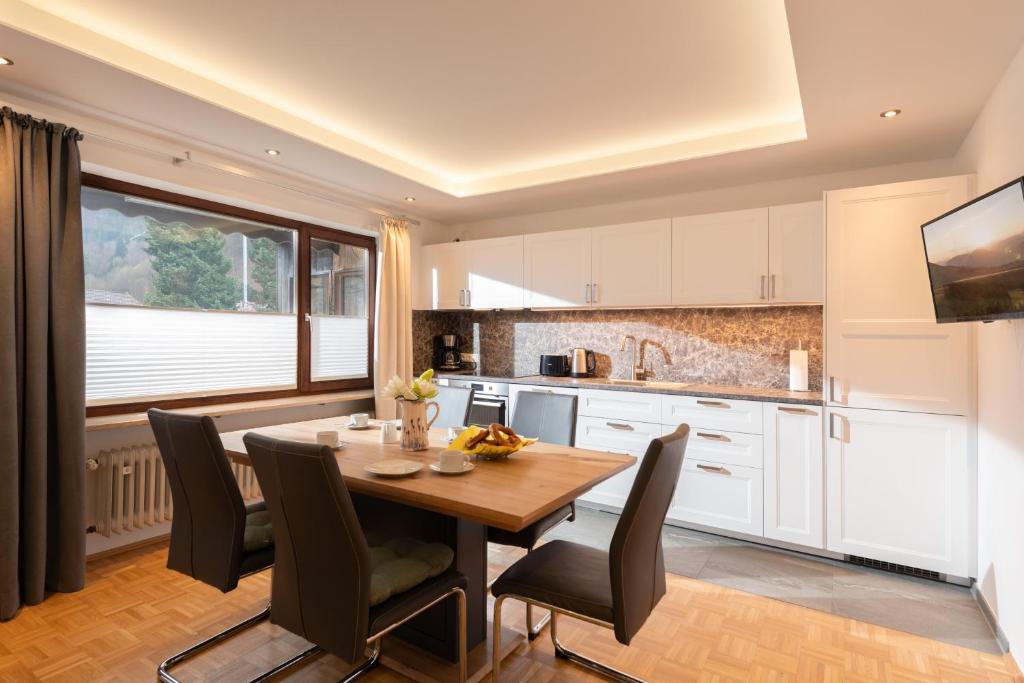 Il comprend une cuisine et une salle à manger avec une table et des chaises en bois. dans l'établissement Ferienhaus Wildbarren - Alpenmagie Suites, à Oberaudorf