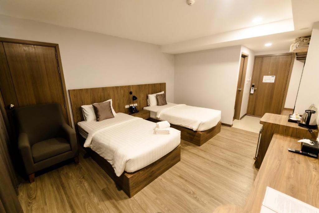 a hotel room with two beds and a chair at Nakara Hotel, Ubon Ratchathani in Ban Na Kham