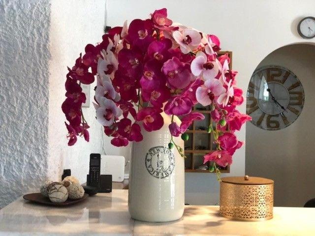 a white vase filled with pink flowers on a table at Karteros Hotel in Karteros