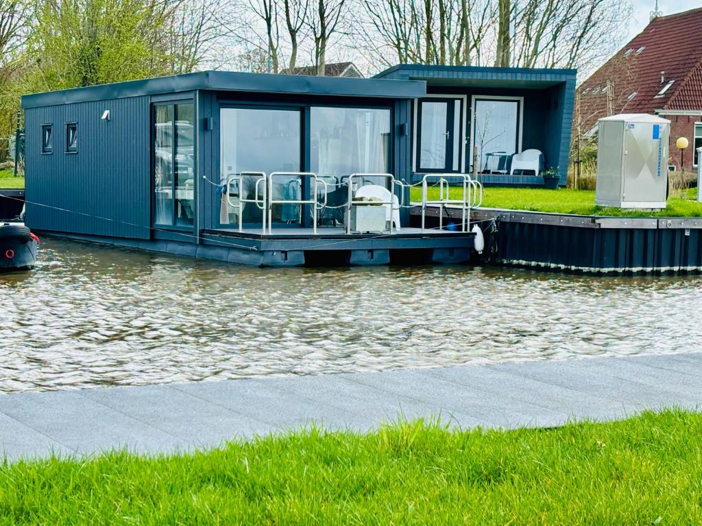 a house on a boat in a body of water at Uniek overnachten in een Tiny House op de Appelhof in Wommels