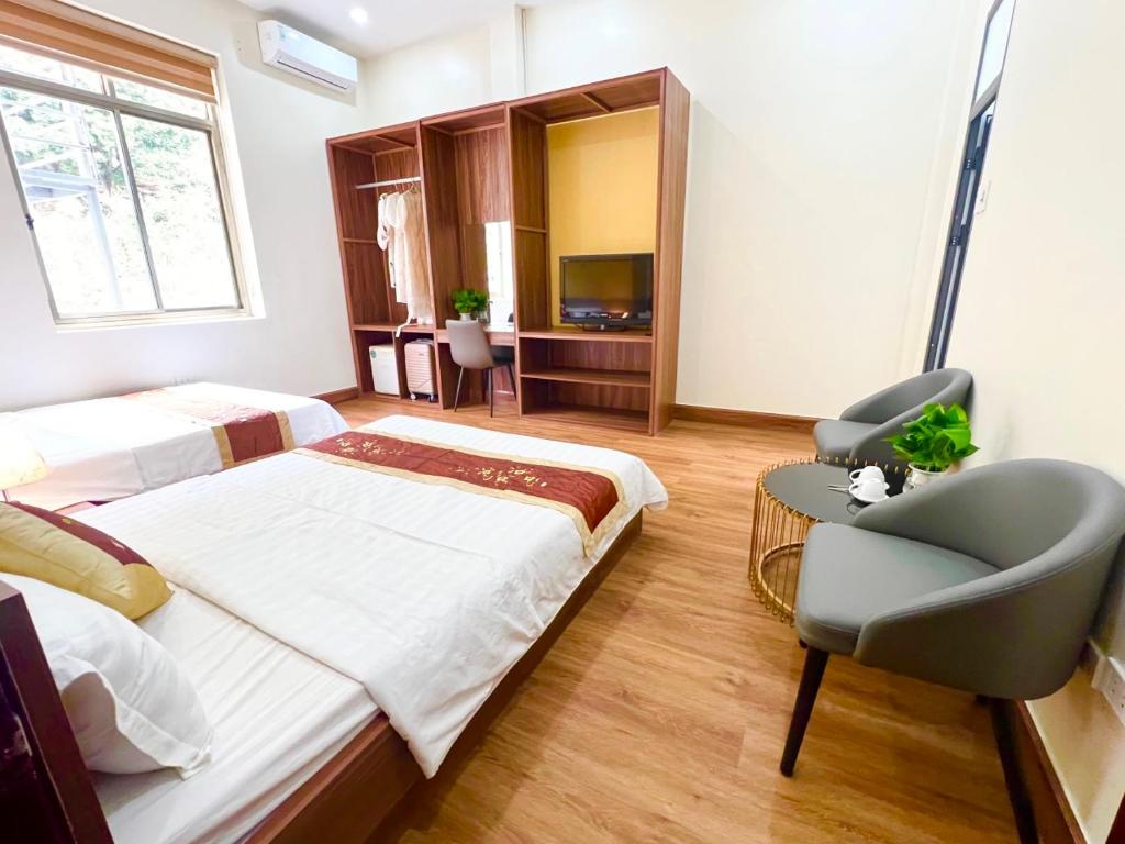a bedroom with two beds and a chair and a television at Gia Cat Long Hotel And Travel in Hai Phong