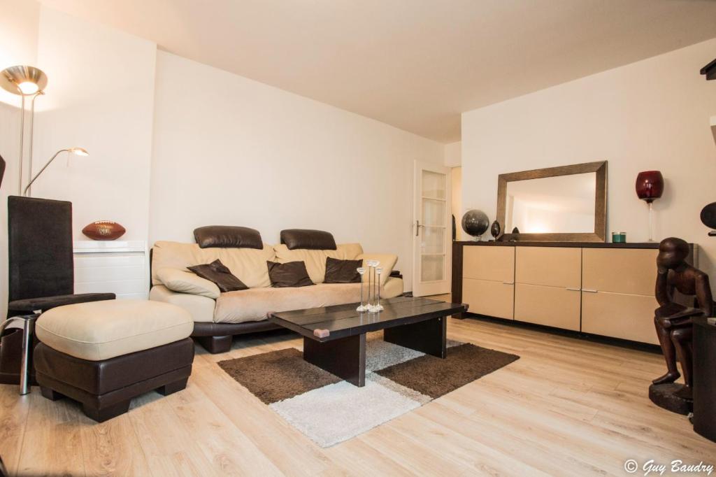 uma sala de estar com um sofá e uma mesa em Chic apart with parking near Paris em Colombes