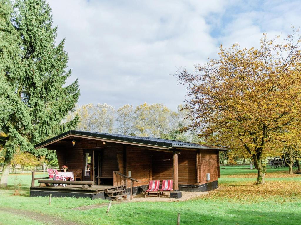 Cabaña de madera con sillas rojas en un campo en Cozy holiday home on a horse farm in the L neburg Heath, en Eschede
