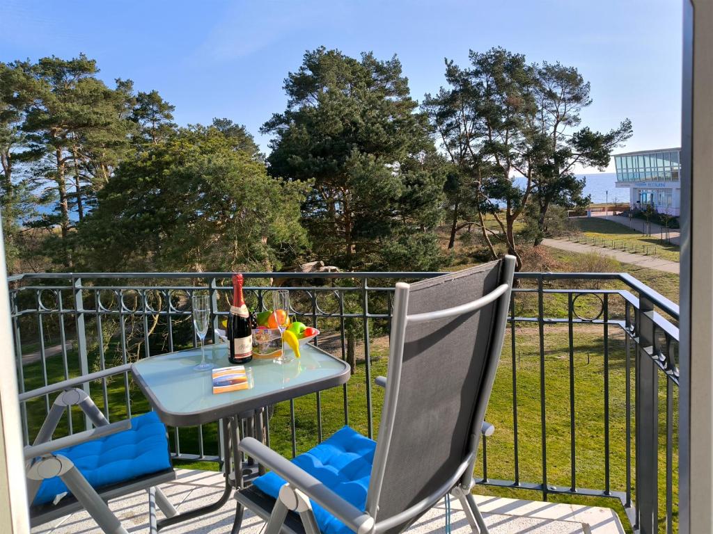 a table and chairs on a balcony with a bottle of wine at Haus Meeresblick - Ferienwohnung Strandloeper C 2.02 (Ref. 134796) in Baabe