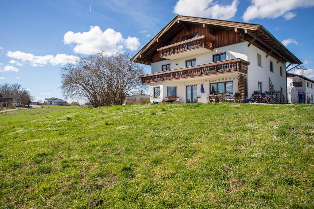 una casa su una collina con un campo verde di Fuchsbau Ferienwohnung am Chiemsee a Seeon-Seebruck