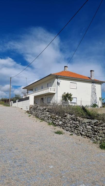 uma casa branca com uma parede de pedra em frente em Villa Mendes Oliva em Almeida