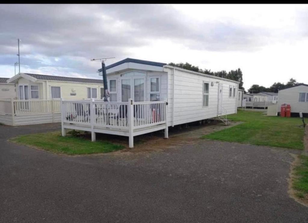 a white mobile home with a porch and a driveway at Cosy static caravan, hunstanton in New Hunstanton