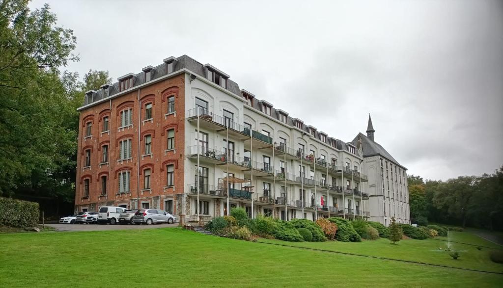 a large brick building with cars parked in front of it at Forest 104 in Vielsalm