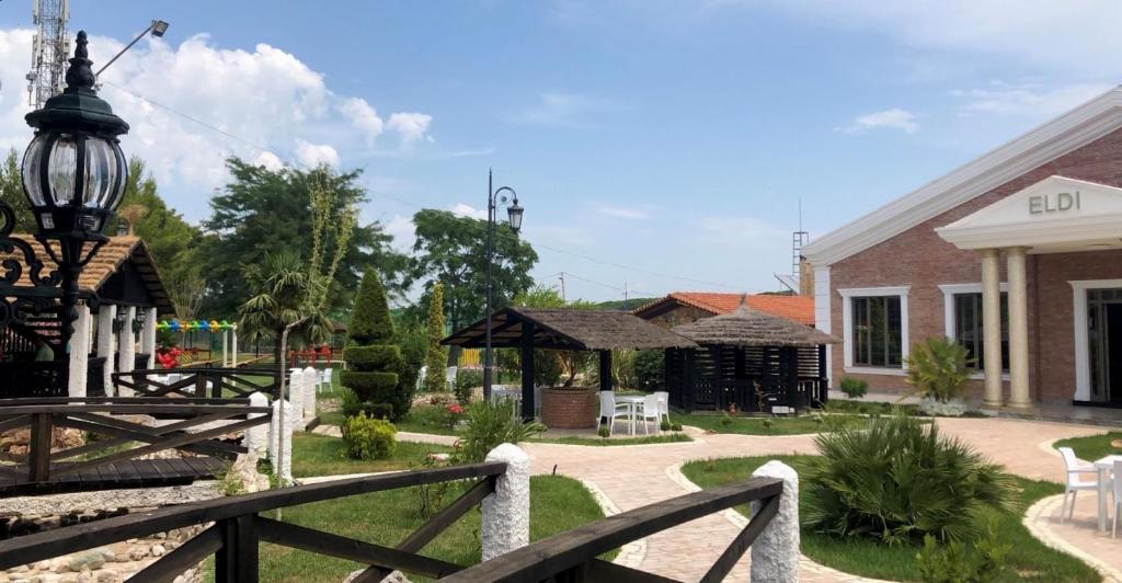 um jardim com uma cerca e um edifício em Agroturizem Eldi em Fier