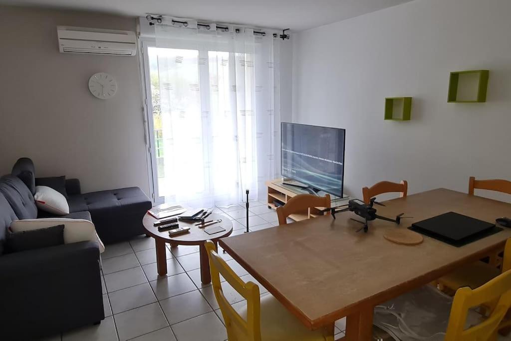 un salon avec une table et une télévision dans l'établissement 2 Chambres-Phonique-Parking sécurisé-Climatisation-DALLE BETON- Géré par Presta-Zen'Services, à Verdun-sur-Meuse