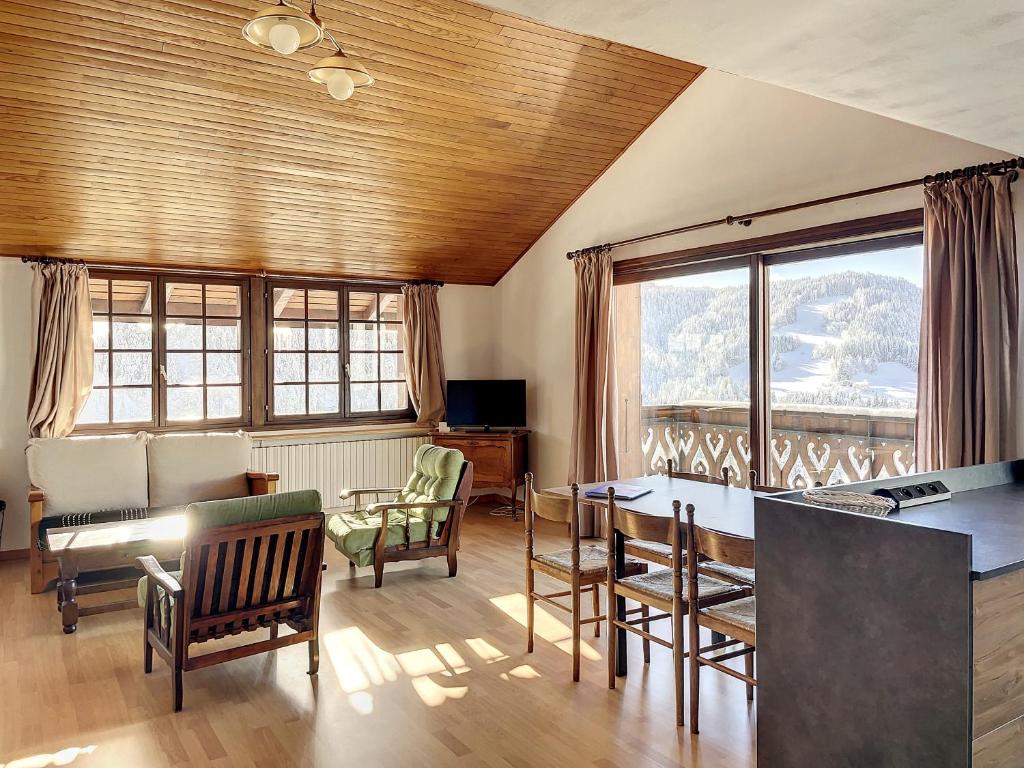 un salon avec une table, des chaises et des fenêtres dans l'établissement Cornuts 3 - appartement - 7pers, aux Gets