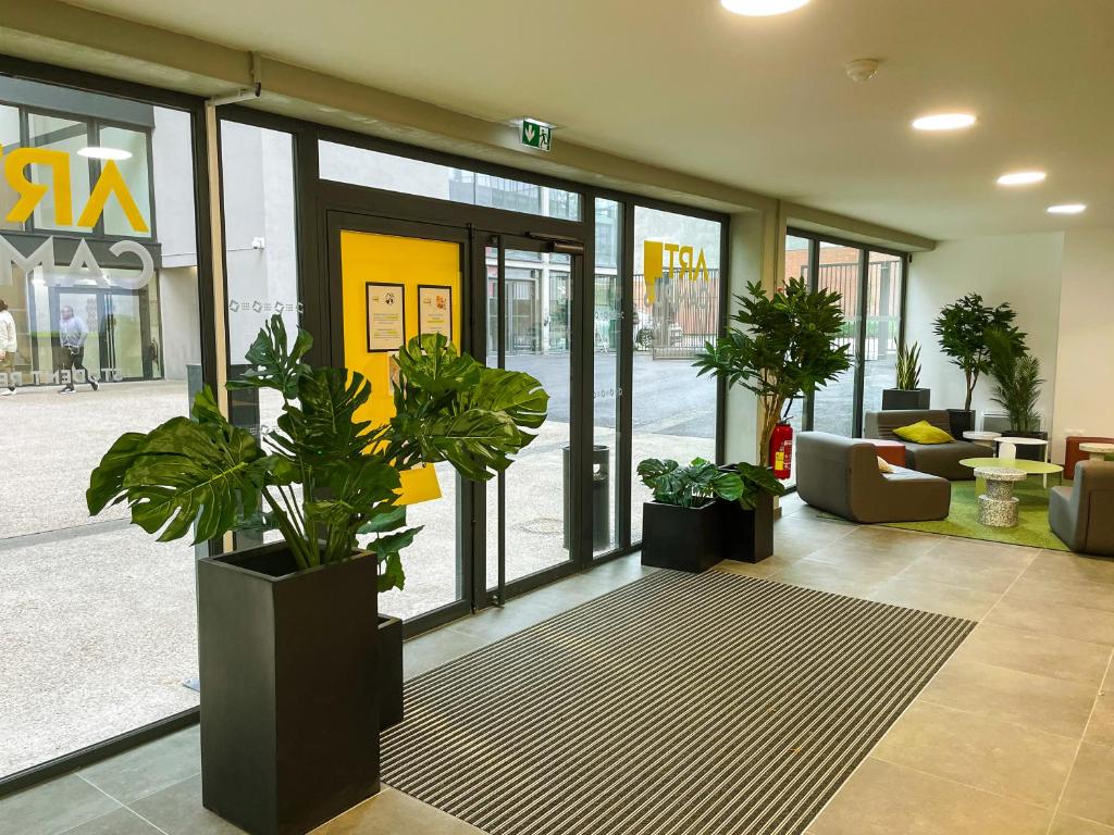 un hall avec des plantes en pot devant un magasin dans l'établissement ART'CAMPUS PLAINE IMAGES, à Roubaix