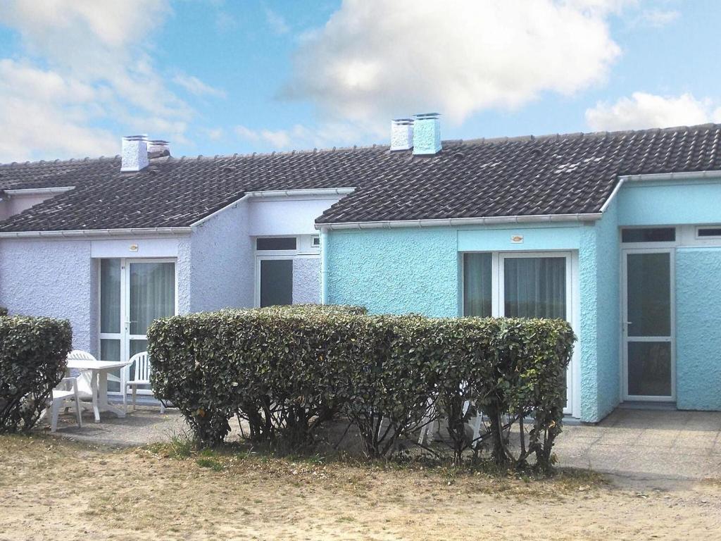 une maison bleue avec une haie devant elle dans l'établissement Les les Anglo Normandes holiday resort Portbail, à Portbail
