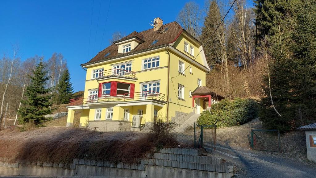 una casa amarilla en la cima de una colina en Villa Weber Apartments en Albrechtice v Jizerských horách