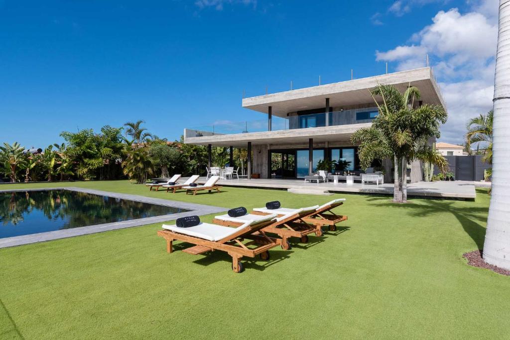 una casa con una piscina y mesas de picnic delante de ella en Karat Atelier de la vega, en Playa Paraiso