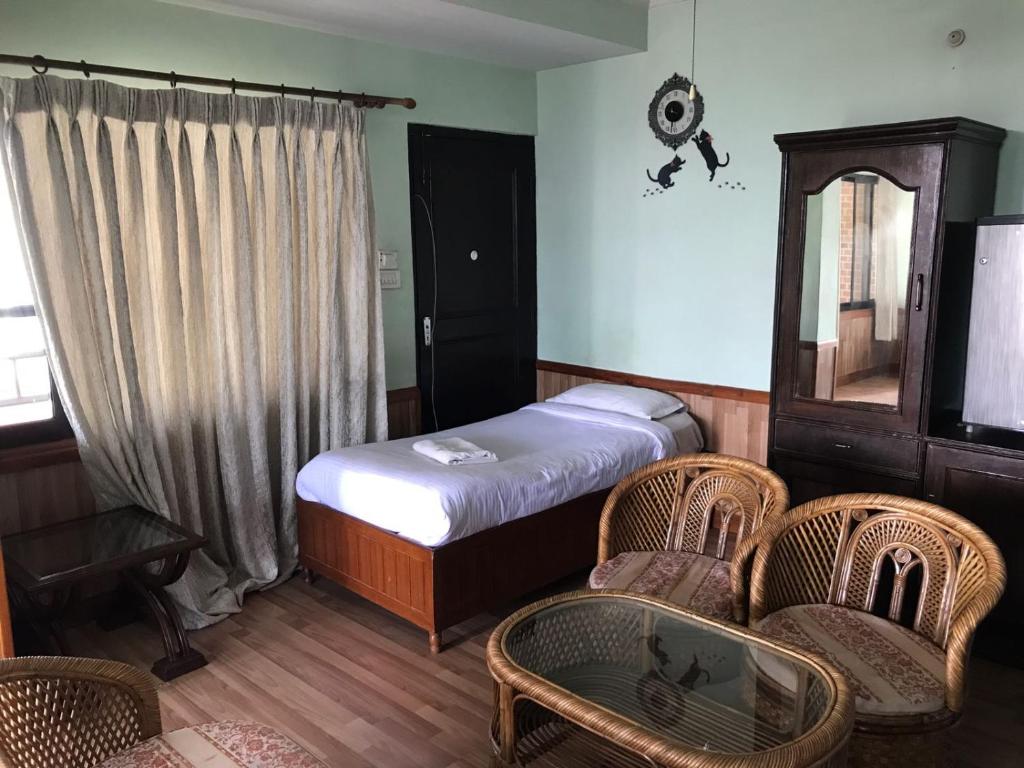 a bedroom with a bed and chairs and a window at Hotel Mandala in Kathmandu