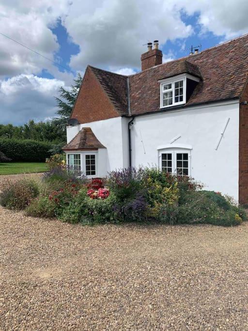 a white house with flowers in front of it at Gullers End Farm Cottage in Long Green
