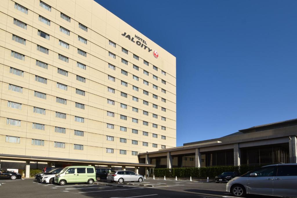 un gran hotel con coches estacionados en un estacionamiento en HOTEL JAL City Tsukuba en Tsukuba
