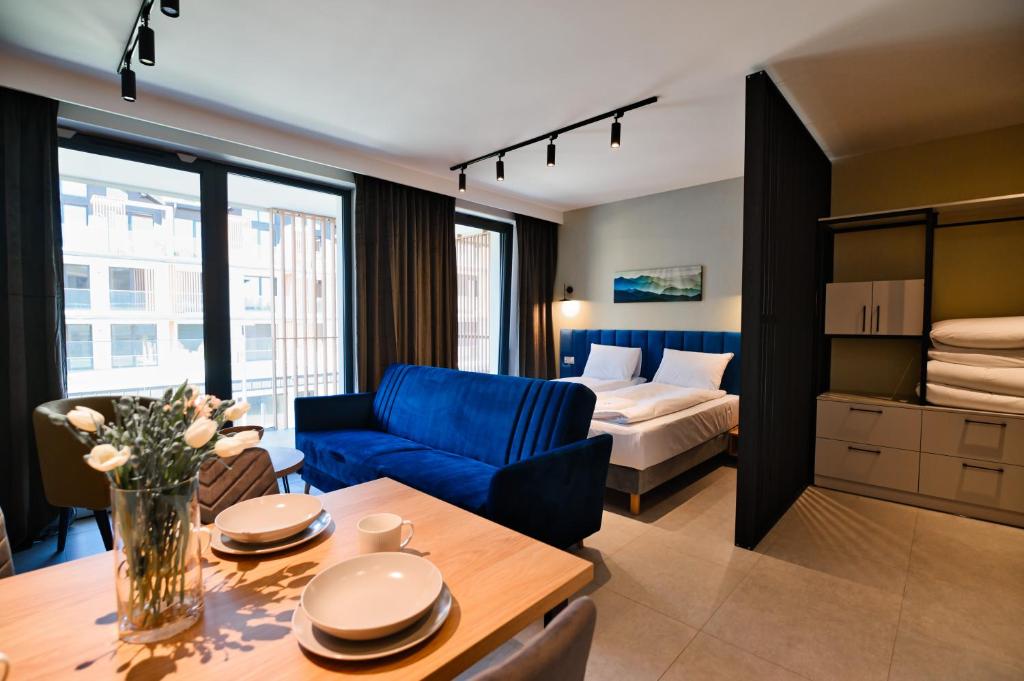 ザジェチェにあるAparthotel Laguna Beskidówのリビングルーム(青いソファ、ベッド付)