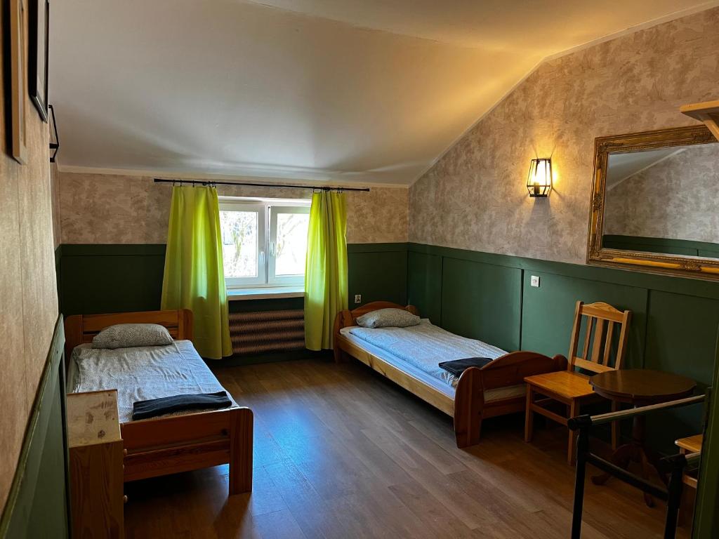 2 łóżka w pokoju z zielonymi ścianami i lustrem w obiekcie Hostel Retro w Krakowie