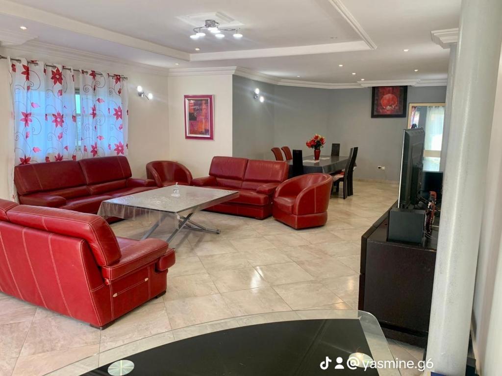 uma sala de estar com mobiliário de couro vermelho e uma mesa em Yasmine Immo em Cotonou