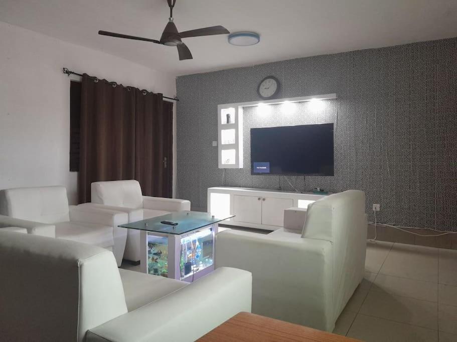 a living room with white furniture and a flat screen tv at Jay's Apt in Takoradi