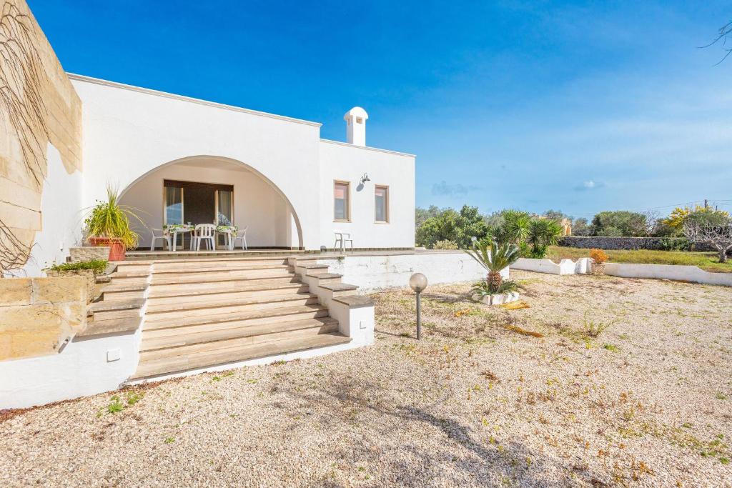 a white house with wooden stairs in a yard at Salentoandmore - Villetta Anna in Marina di Pescoluse