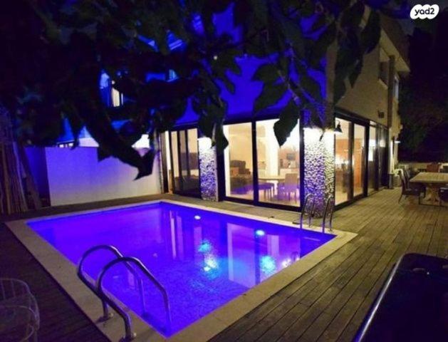 einen Pool mit lila Beleuchtung in einem Haus in der Unterkunft אחוזת פרישמן in Herzliya B