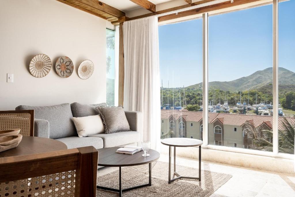 ein Wohnzimmer mit einem Sofa und einem großen Fenster in der Unterkunft Cofresi Hills Residence in Gurapito