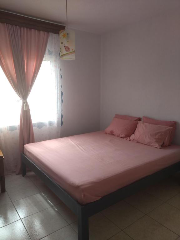 a bed with pink sheets in a room with a window at AGAPI'S HOUSE in Sidhirókastron