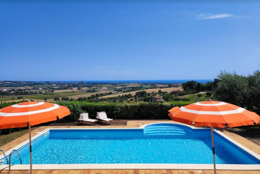 una piscina con 2 sombrillas y una piscina en agriturismo contrada del raglio, en Potenza Picena