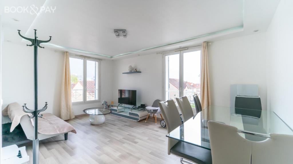 un soggiorno con pareti e finestre bianche di Appartement 60m² à 20 min de Paris a Romainville