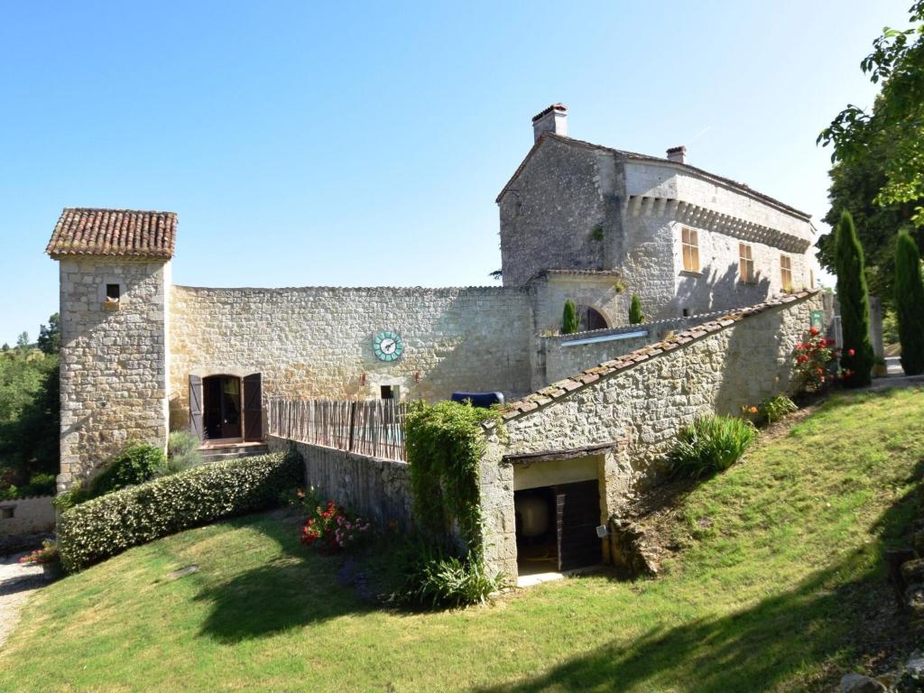 un antiguo edificio de piedra en una colina con un patio en Castle 12th century with private pool close to Agen, en Saint-Caprais-de-Lerm