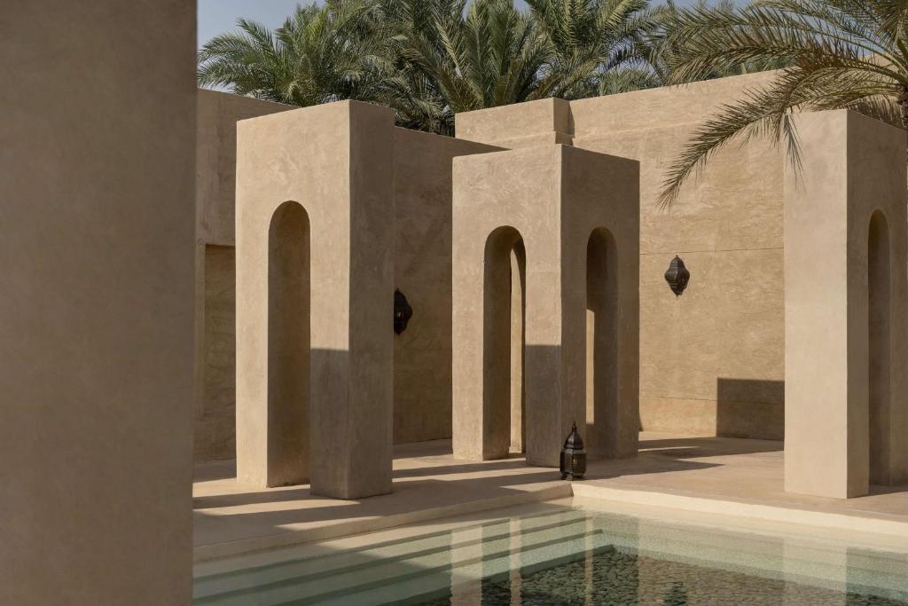 Bab Al Shams, A Rare Finds Desert Resort, Dubai في دبي: مبنى به مسبح و نخيل