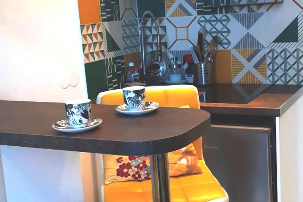 uma mesa preta com duas chávenas e uma cadeira amarela em Charmant studio au Pecq / Saint-germain en laye. em Le Pecq