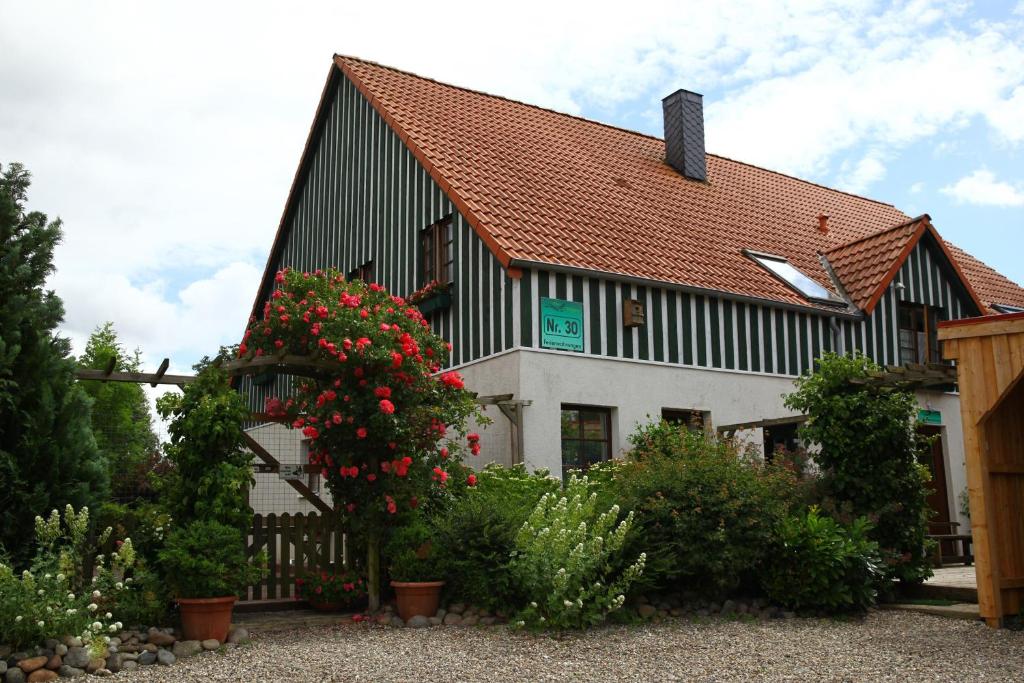 a black and white building with flowers in front of it at Haus Wildgans Ferienwohnung Rose in Behrensdorf