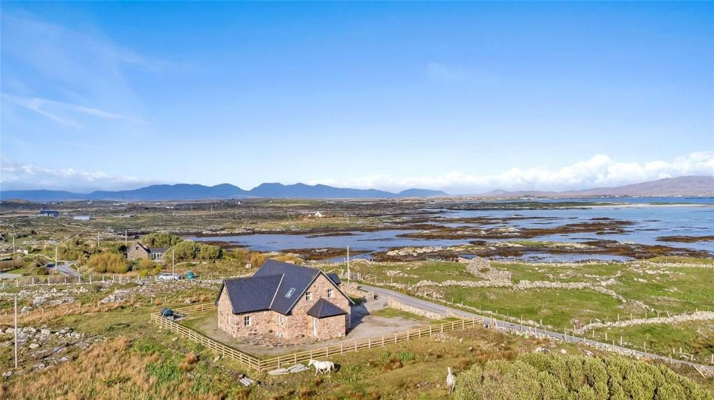an aerial view of an old house in a field next to a river at 412 Bunowen Cottage in Ballyconneely