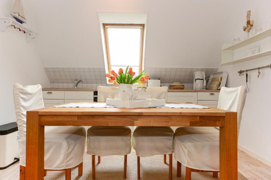 een keuken met een houten tafel met witte stoelen bij Haus Bonken - a72764 in Wyk auf Föhr
