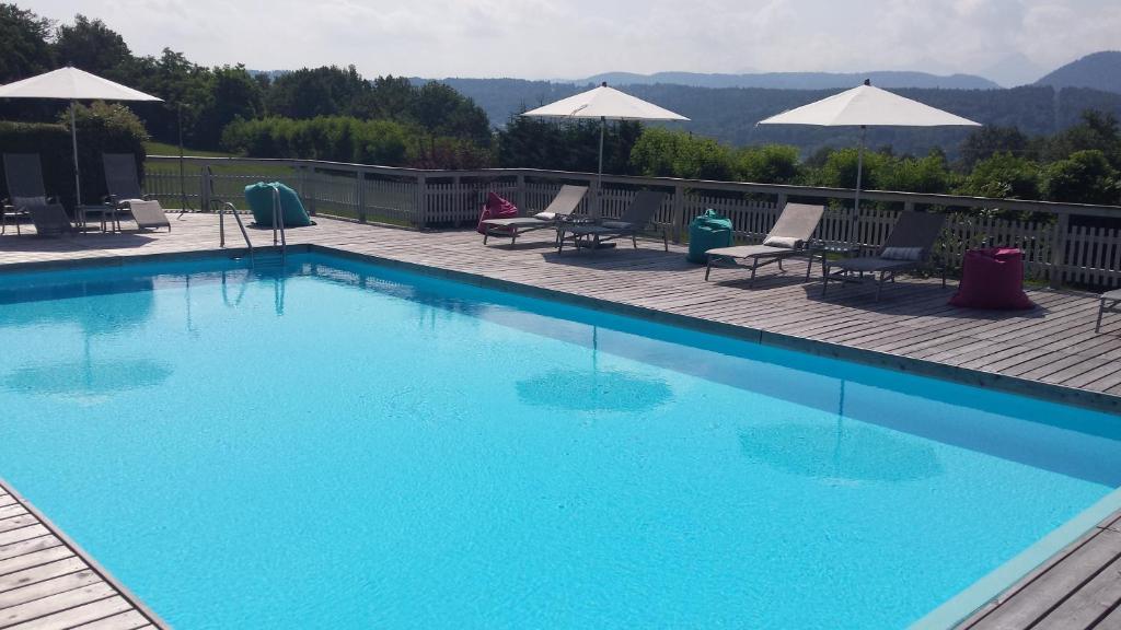 a large blue swimming pool with chairs and umbrellas at Hotel Garni Wurzer in Velden am Wörthersee