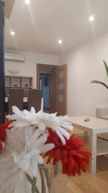 a vase with white and red flowers in a room at Laura House The Style Airport BCN in Viladecáns