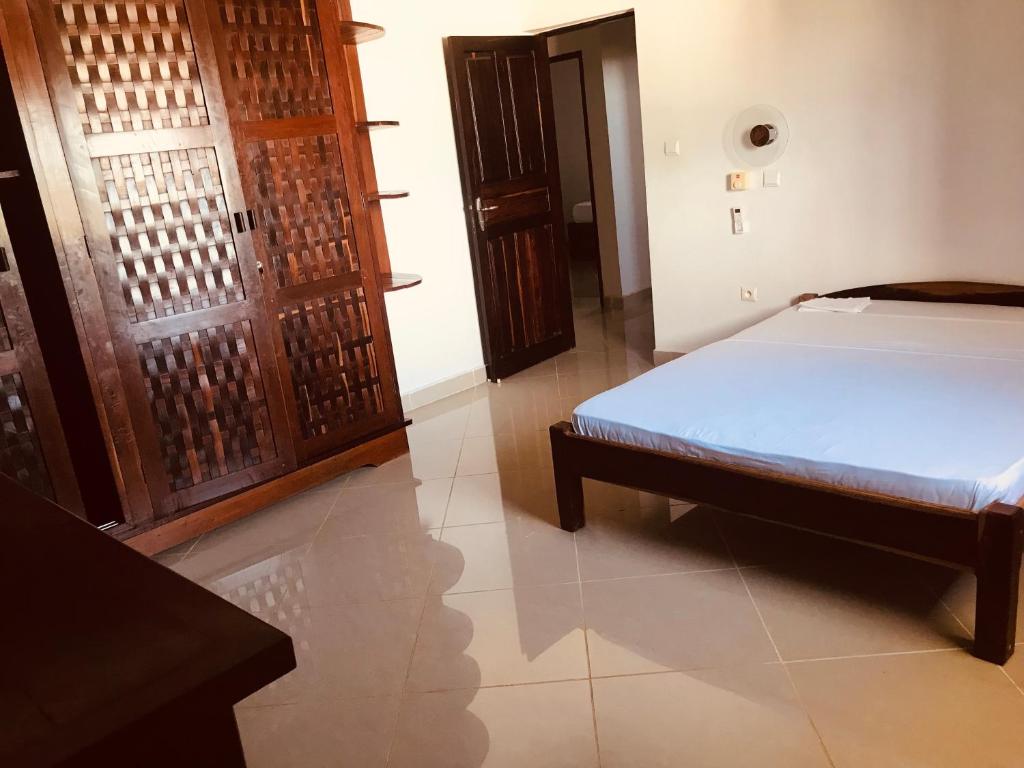 um quarto com uma cama e uma porta de madeira em Villa hafaliana em Nosy-Be